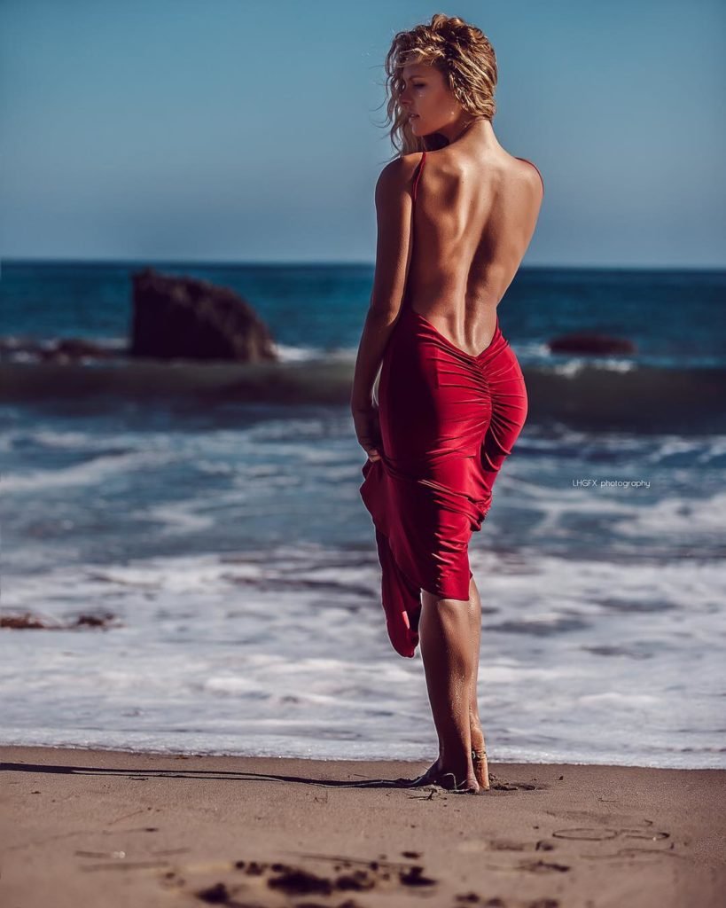 Meridith Mack  Modelo loira Segurando o Vestido na areia da Praia