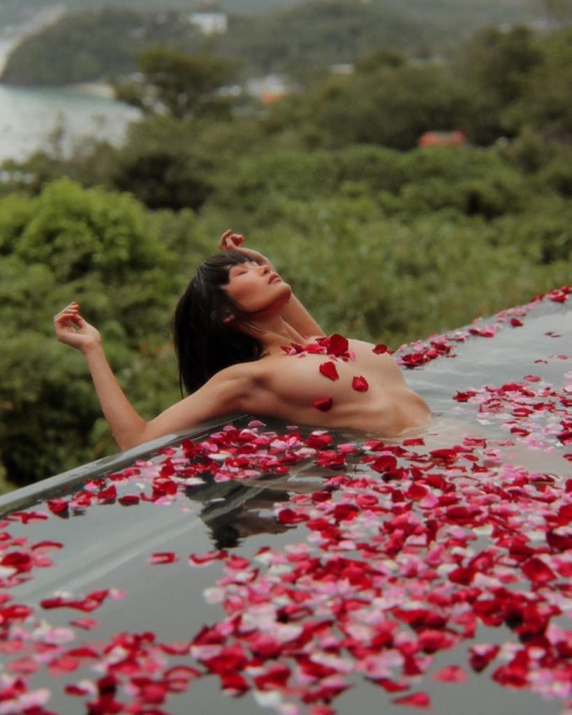 Modelo Oriental na piscina nua com rosas