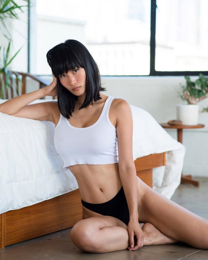 Miki Hamano Modelo Orinetal sentada no chão perto da cama