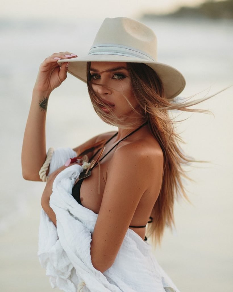 Borbala K modelo loira em foto na praia com chapéu