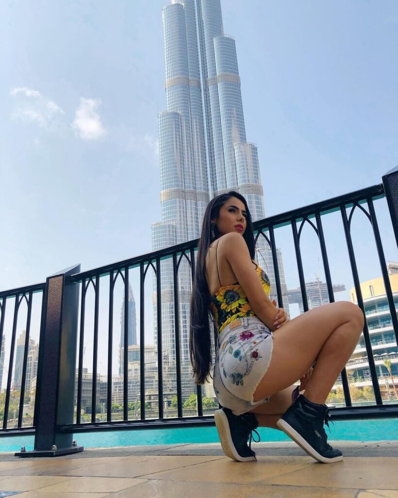 Juliana Bonde em Dubai posando agachada de shortinhos Jeans