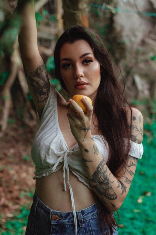  Mabelle alt-model e fotógrafa de blusinha branca e fruta na mão 