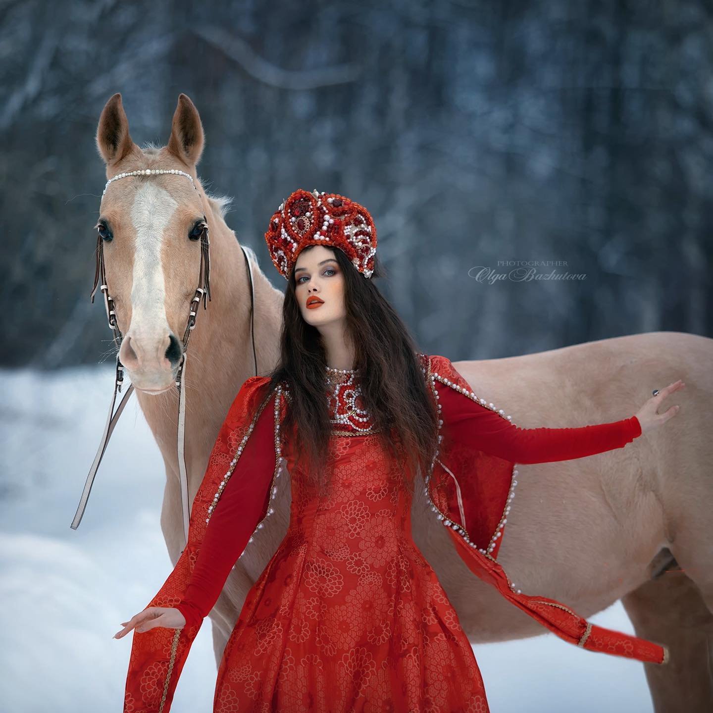 Olga Bazhutova fotografia equestre - Modelo posando com cavalo na neve de figurino vermelho
